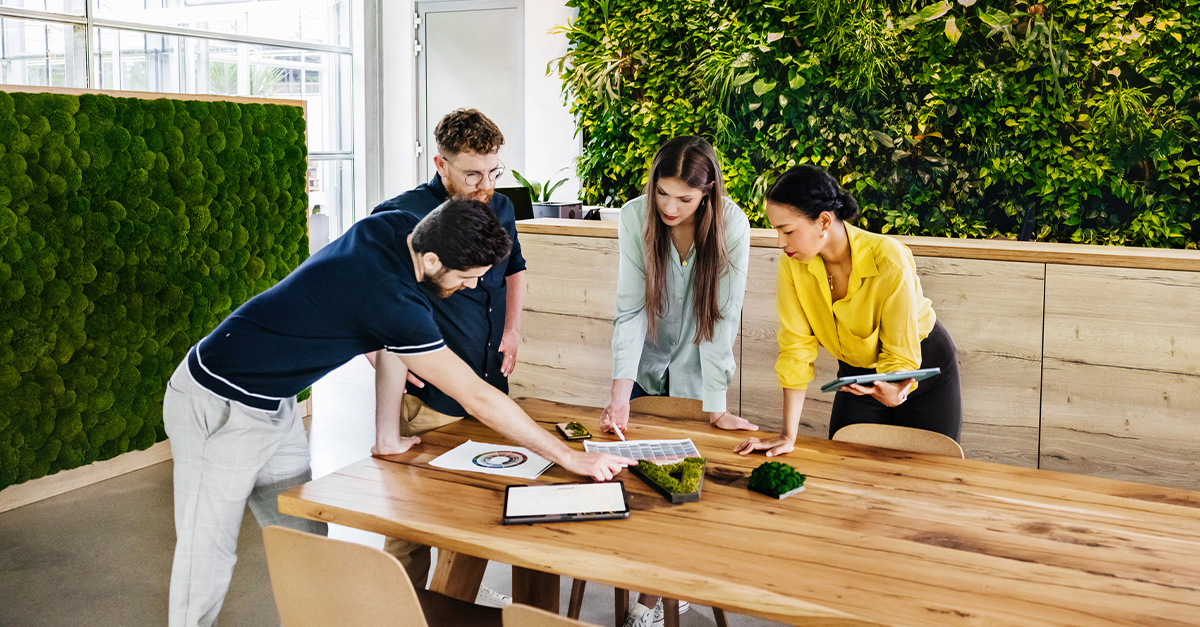 Gruppo di 4 persone che lavorano intorno ad un tavolo all'interno di un ufficio.
