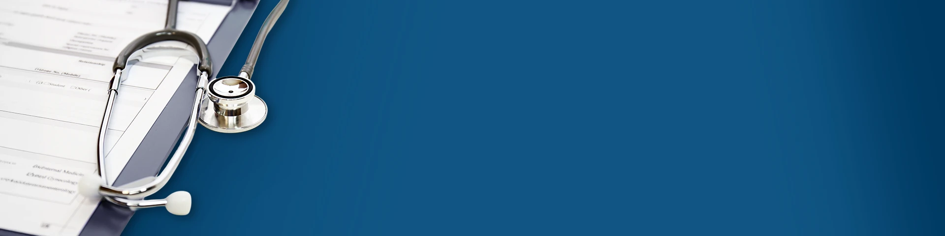 Stetoscopio d'argento e grigio appoggiato su una cartella clinica con moduli cartacei sparsi. Gli oggetti sono su uno sfondo blu scuro uniforme.