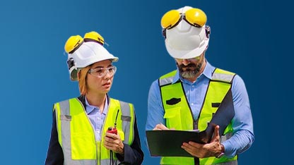 Due ingegneri, un uomo e una donna, in piedi fianco a fianco su uno sfondo blu solido. Entrambi indossano caschi bianchi con paraorecchie protettivi gialli e giubbotti di sicurezza giallo-verdi riflettenti. La donna, a sinistra, guarda verso l'alto con un'espressione pensierosa, tenendo una radio bidirezionale in mano. L'uomo, a destra, guarda in basso mentre scrive o esamina dei documenti su una cartellina nera. L'illuminazione è luminosa e uniforme.