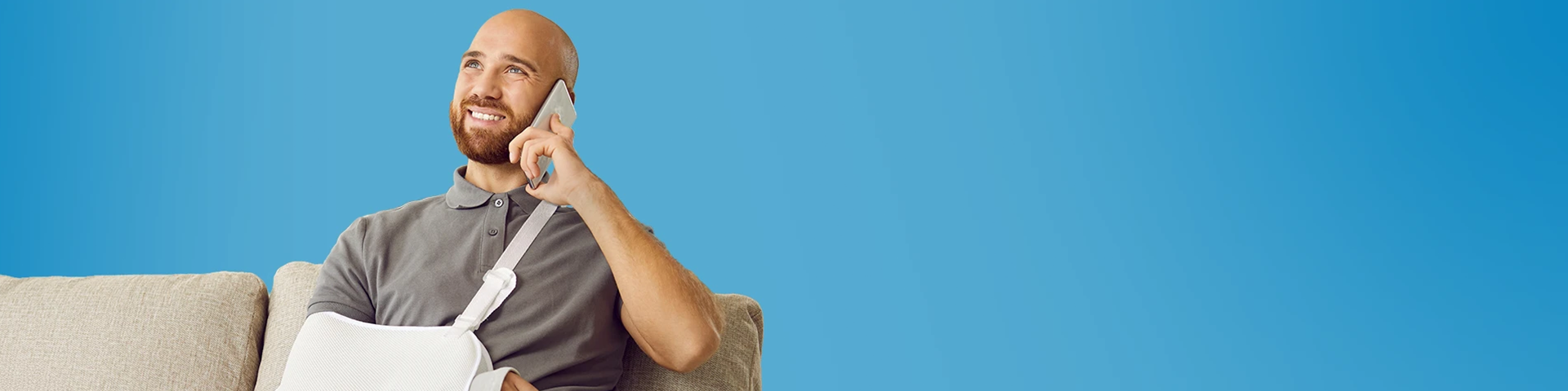 Uomo sorridente con un braccio rotto che parla al telefono