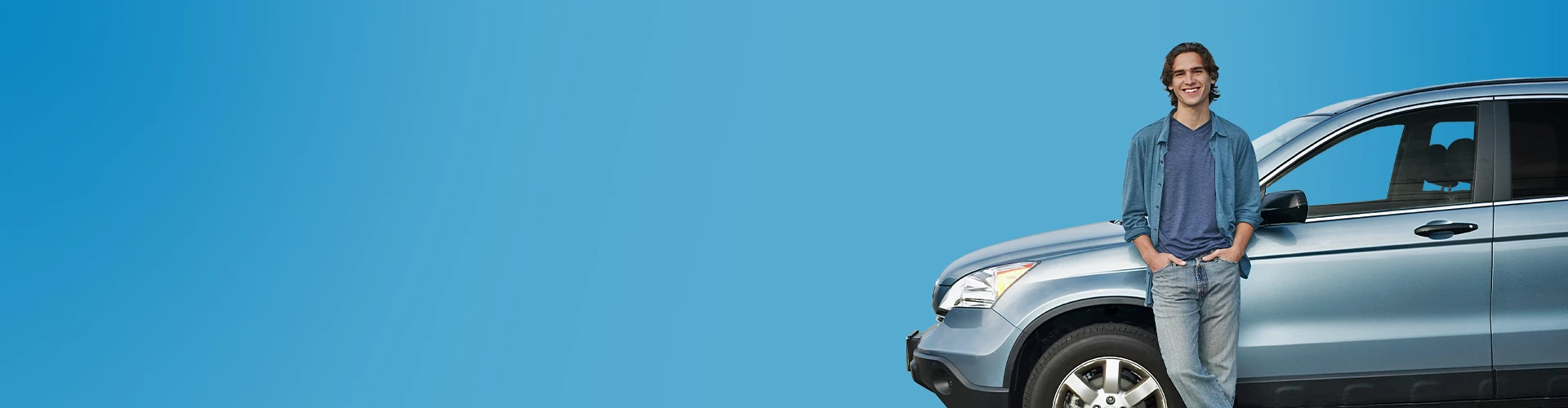 Giovane uomo sorridente appoggiato ad una macchina