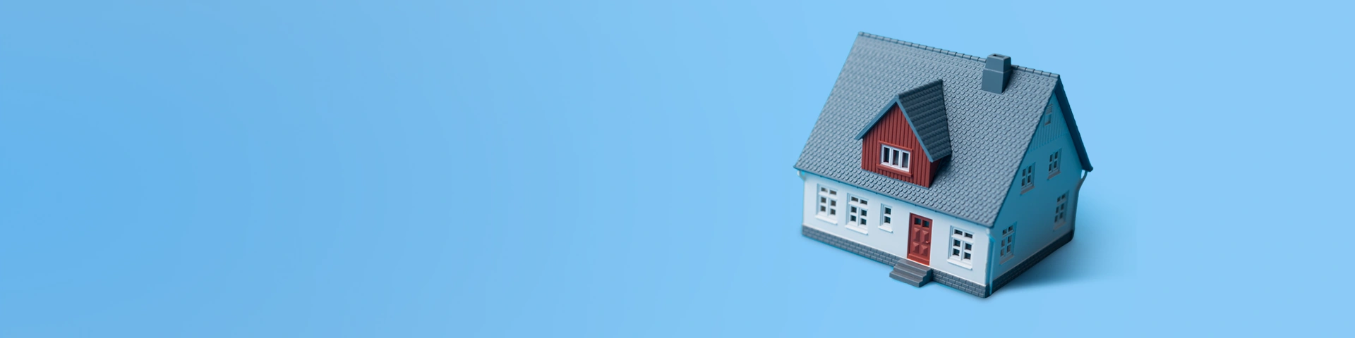 Modellino di casa su sfondo azzurro