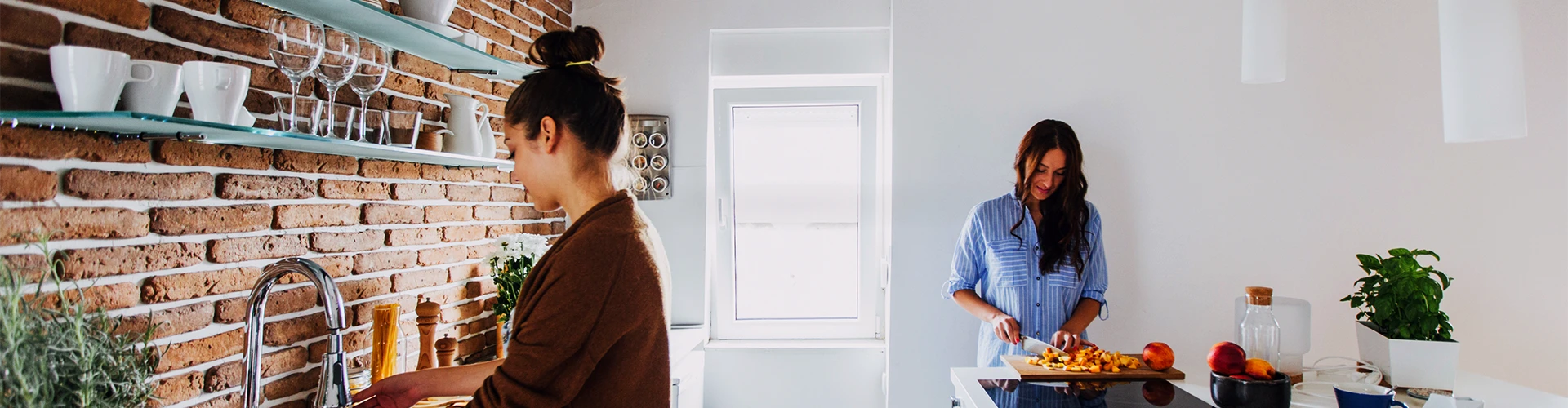 Giovane donna davanti al lavandino della cucina e giovane donna che taglia le verdure