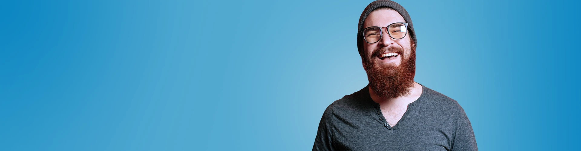 Giovane uomo sorridente con baba, occhiali e cappello