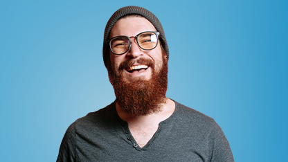 Giovane uomo sorridente con barba, occhiali e cappello