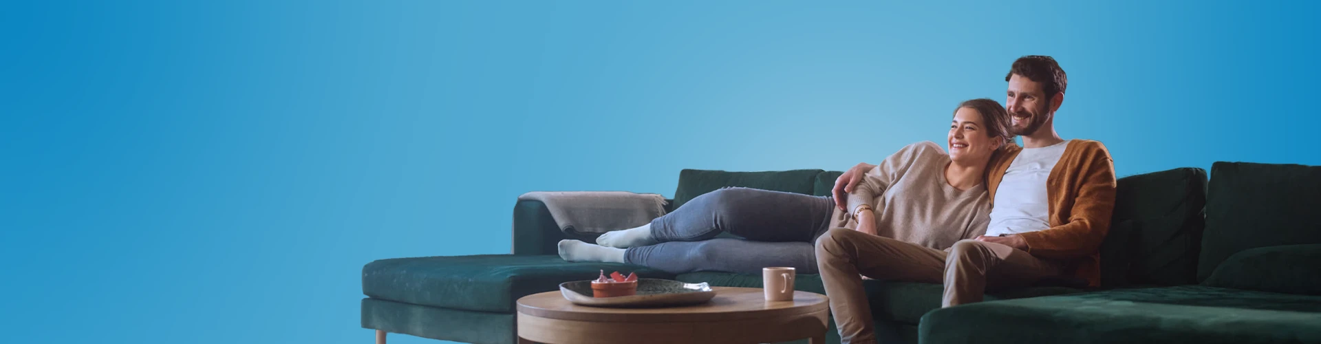 Uomo e donna sorridenti abbracciati sul divano