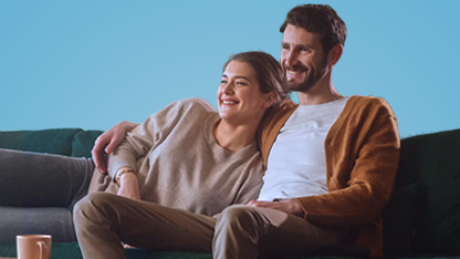 Uomo e donna sorridenti abbracciati sul divano