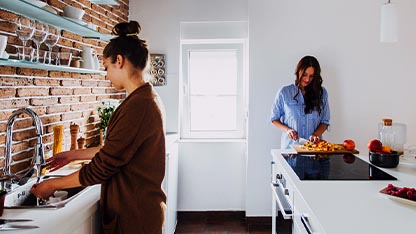 Un uomo e una donna sorridenti con in mano un modellino di casa e un mazzo di chiavi