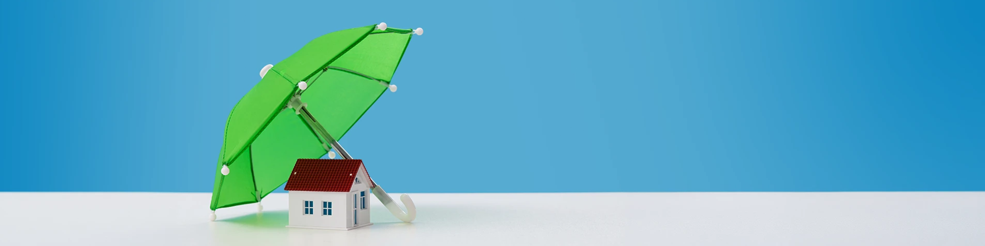 Modellino di casa coperto da un ombrello verde