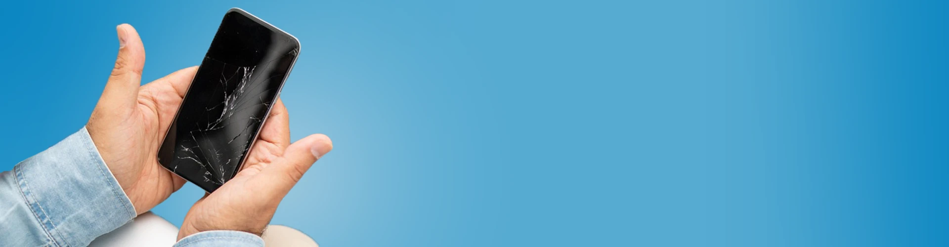 Due mani che tengono uno smartphone  spento con il vetro rotto